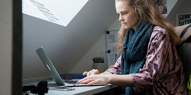 En dame som sitter foran PC på et hjemmekontor. Foto.