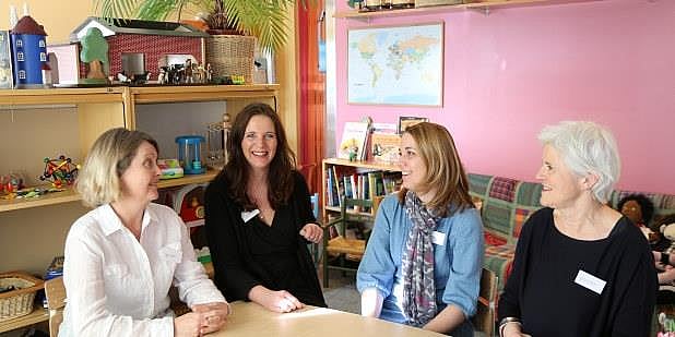 Samtale mellom fire damer ved et bord i en barnehage. Foto.