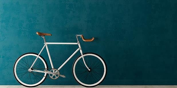 Sykkel lent mot blå vegg. Foto.