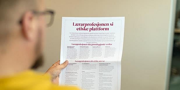 Person ser på plakat av lærerprofesjonens etiske plattform. Foto.