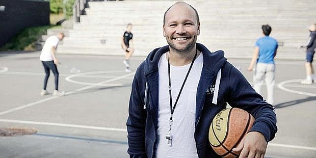 Mann med basketball som smiler. Foto.