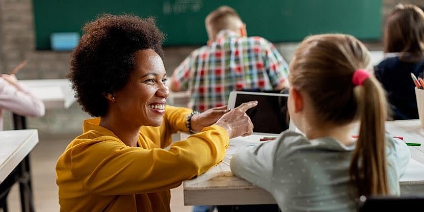 Kvinnelig lærer på huk med en elev i klasserommet