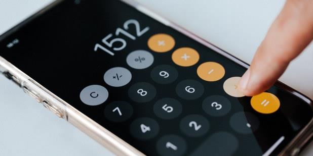 Finger som trykker på kalkulator på en mobilskjerm 