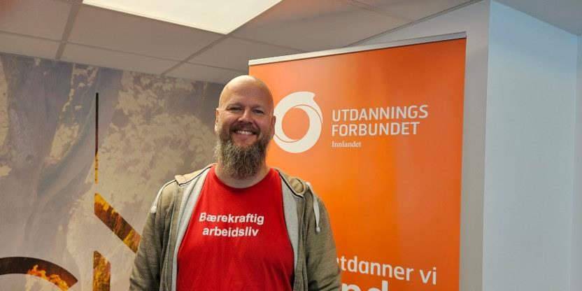 Bilde av en smilende fylkesleder Thore Johan Nærbøer for an en rollup med Utdanningsforbundets logo