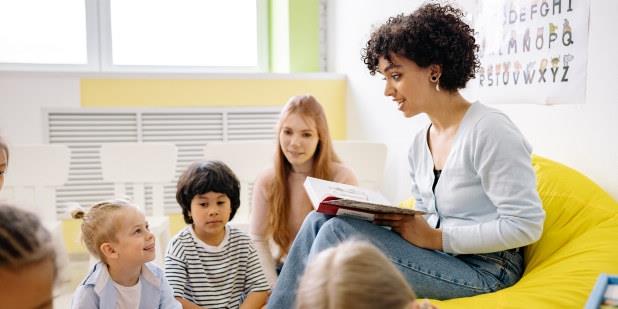 Barnehagelærer leser høyt for liten gruppe barn. Fotografi