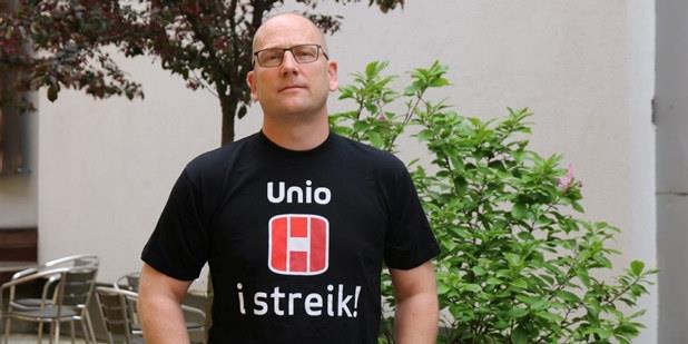 Leder i Utdanningsforbundet, Steffen Handal, står i "Unio i streik" T-skjorte. Han ser alvorlig ut. Bildet er tatt ute med en grønn busk i bakgrunnen.