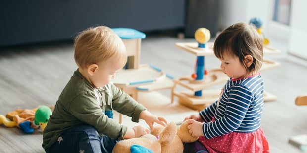 To barnehagebarn sitter og leker sammen på gulvet. Illustrasjonsfoto.