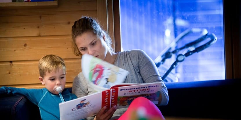En barnehageansatt leser for et barn - foto