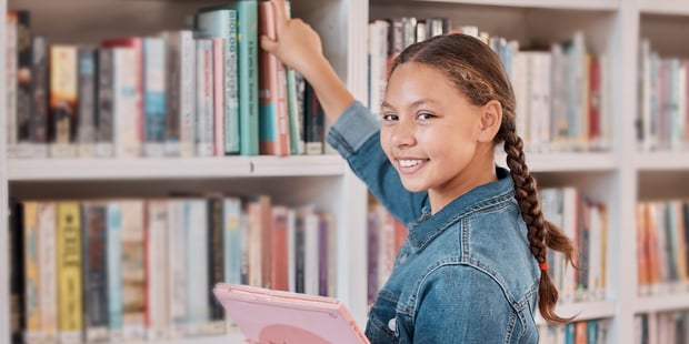 smilende jente på biblioteket