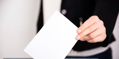 Person legger en stemmeseddel i en valgboks