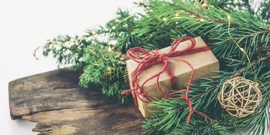 Juledekorasjon med pakke og granbarkvister på en trefjøl. Foto