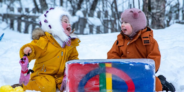 To barn som koser seg og leker ute i snøen