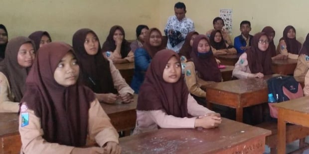 Elever i et klasserom i Indonesia, sammen med læreren sin