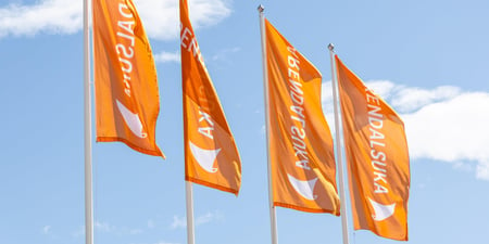 Flagg med orange Arendalsuka-logo som flagrer mot blå himmel