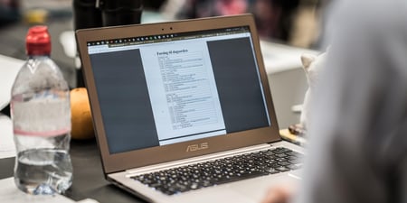 Bilde av tastatur og pc skjerm samt en person som sitter ved skjermen