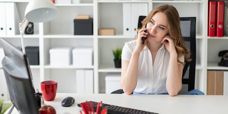 Young girl is sitting in the office and talking on the phone.