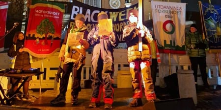 Tre ungdommer holder appel på en scene foran Rådhuset, med plakater. Mange
organisasjonsfaner bak, blant annet fanen til Utdanningsforbundet Oslo