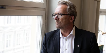 Geir Røsvoll sitter i en vinduskarm og stirrer bekymret ut av vinduet.