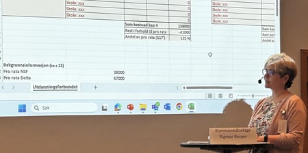 Kvinnelig presentatør viser et regneark på skjermen. Foto.