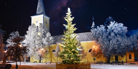 Bildet viser en kirke i mørket. Det er snø, og man får julefølelse.