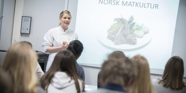 Undervisning i klasserom, Lærer underviser foran elektronisk tavle. Illustrasjonsfoto