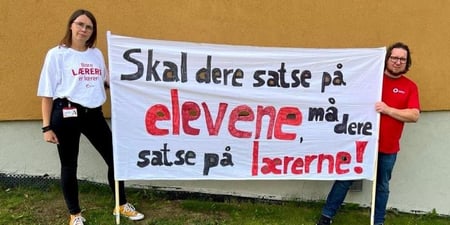 Bilde av lokallagsleder Gunhild Grindjordet og nestleder Roar Busterud med banner som sier skal dere satse på elevene, må dere satse på lærerne