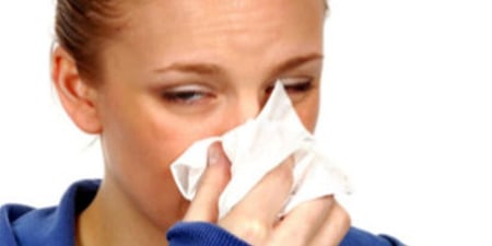 Bilde av en kvinne som tørker nese, ser syk ut.