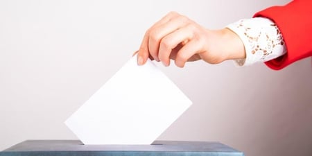En arm og hånd legger en stemmeseddel i en stemmeboks