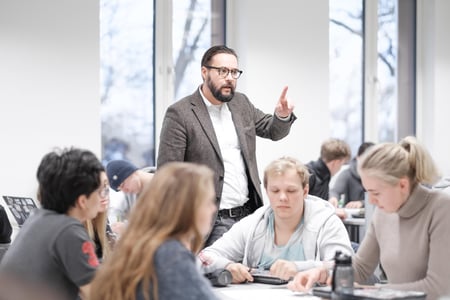 En mannlig lærer/lektor står foran elevene i klasserommet på en videregående skole og prater. Illustrasjonsfoto.