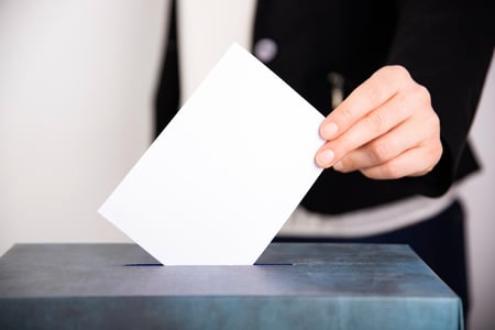 Person legger en stemmeseddel i en valgboks