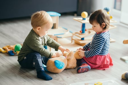 To barnehagebarn sitter og leker sammen på gulvet. Illustrasjonsfoto.