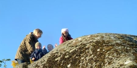 Barn og en voksen som leker ute i naturen. Foto.