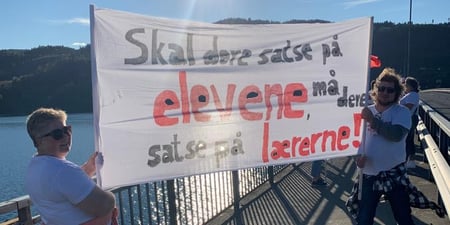 Bilde fra streikemarkering på Mjøsbrua. Stine Grinden Pettersen og Roar Busterud holder en banner med påskrift: Skal dere satse på elevene, må dere satse på lærerne.