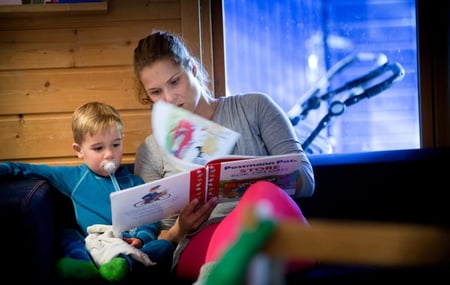 En barnehageansatt leser for et barn - foto