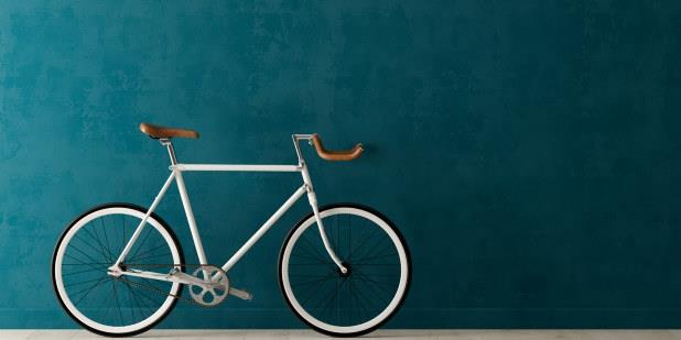 Sykkel lent mot blå vegg. Foto.