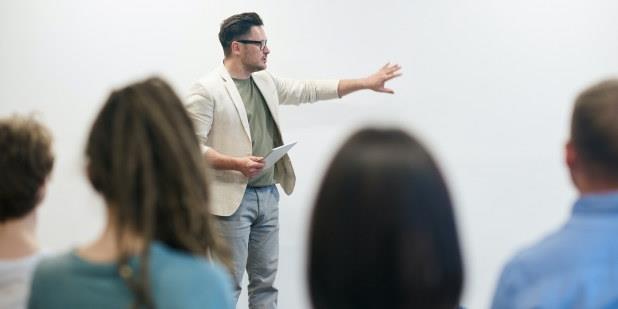 Lærer står foran studenter og forklarer. Illustrasjonsfoto