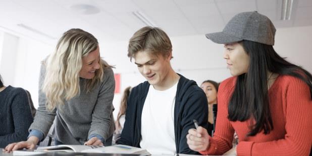 Illustrasjonsbilde av to studenter med lærer som alle smiler. 