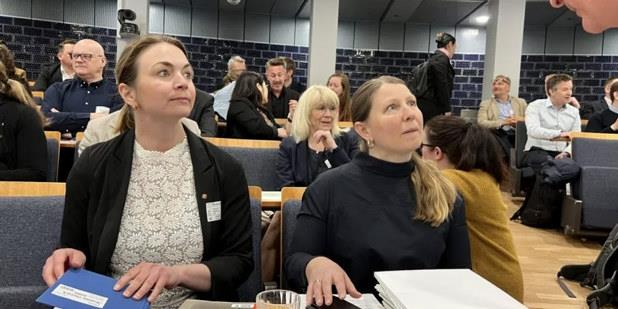 Foto av to kvinner med dokumenterer som diskuterer med en mann utenfor bildet.