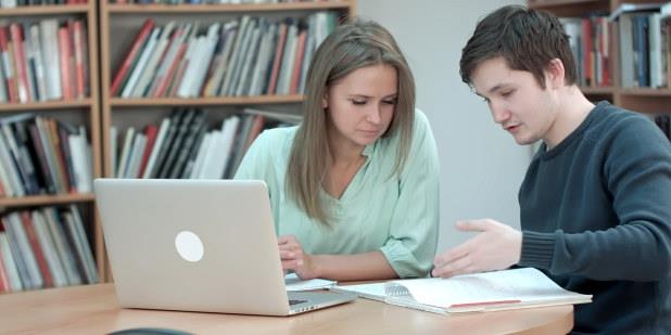 To studenter samarbeider foran en pc. Illustrasjonsfoto.