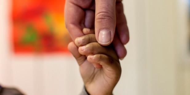 En voksens hånd holder et barns hånd.