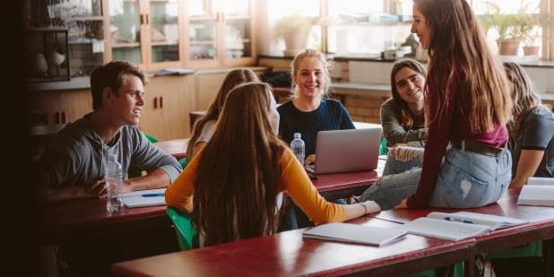 En gruppe studenter samtaler i et klasserom. Illustrasjonsfoto