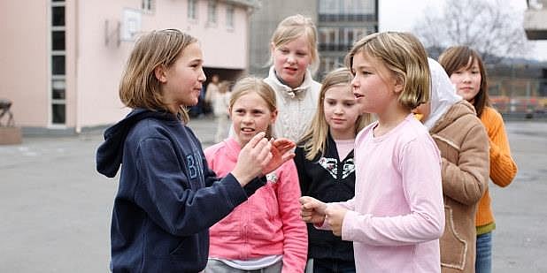En gruppe jenter i skolegården leker i et friminutt. Foto.