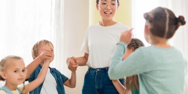 Lærer som leker med små skoleelever. Ilustrasjonsfoto