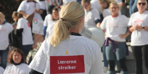 Foto av streikende kvinnelig lærer bakfra med ropert. I bakgrunnen ses mange streikende lærere