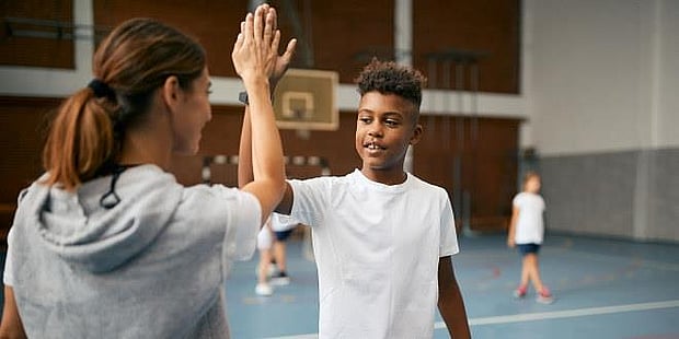 Illustrasjonsfoto av kvinnelig kroppsøvingslærer som gir en "high five" til en elev
