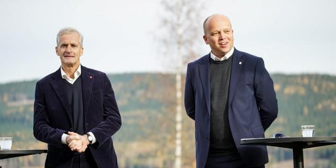 Jonas Gahr Støre og Trygve Slagsvold Vedum på pressekonferanse om regjeringserklæringen på Hurdalsjøen. De står foran et tre, smiler fornøyde, og hver av dem har et glass vann ved siden av seg.