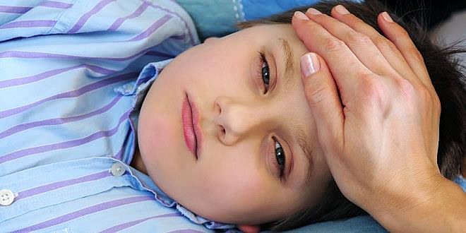 Illustrasjonsfoto av sykt barn i sengen med morens hånd på pannen