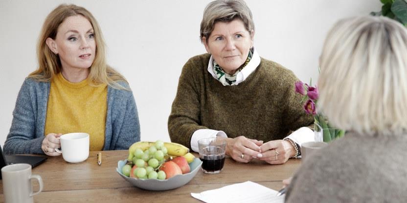 Tre damer sitter rundt et bord og fyller ut skjema.