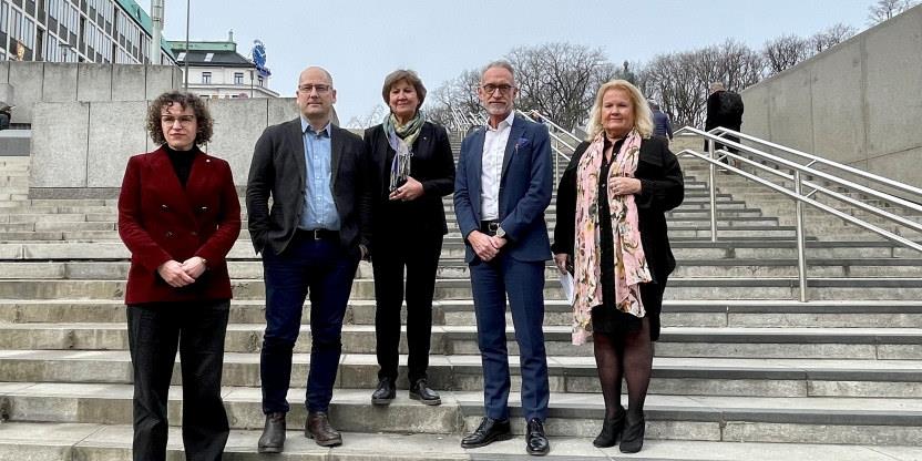 Fem mennesker samlet på en trapp nedenfor Utenriksdept. 